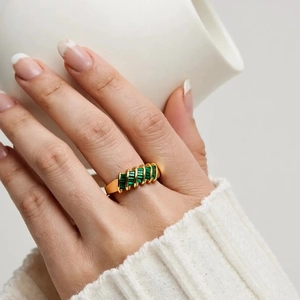 Detailed view of 18K gold plated ring with emerald-cut green zircons worn on finger