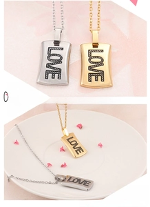 Detailed macro of silver and gold rectangular pendants with LOVE engraving and fine chain