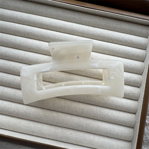 Detail of rectangular marble texture hair claw clip in a velvet jewelry box display