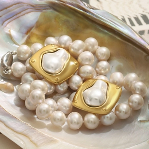 Détail macro d'un collier de perles vintage avec accents dorés dans un coquillage
