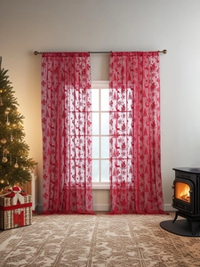 Détail de rideaux de Noël en dentelle rouge avec motifs rennes et sapins dans une pièce