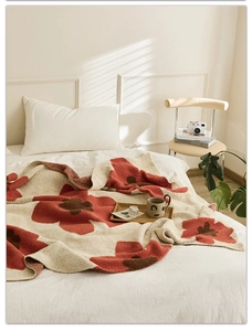 Close-up of Nordic knitted blanket featuring bold orange floral patterns on a beige base