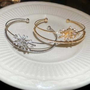 Detail view of snowflake zircon and pearl bangle set on elegant ceramic plate background