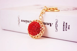 Close-up of golden keychain with red rhinestones and polished circular design