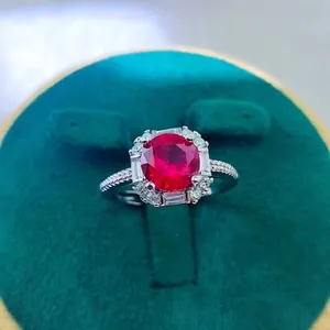 Macro shot of 2ct oval red ruby ring with halo diamonds on green velvet box