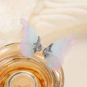 Close-up of blue tulle butterfly earrings with sparkling cubic zirconia on a glass rim