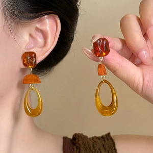 Detail of amber resin drop earrings featuring geometric shapes on a model and close-up