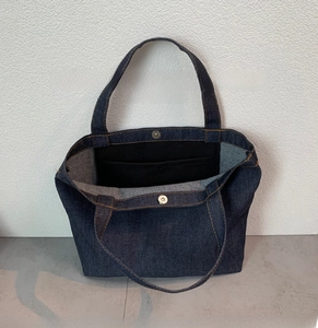 Detail view of denim lunch bag interior with magnetic buckle and storage pocket