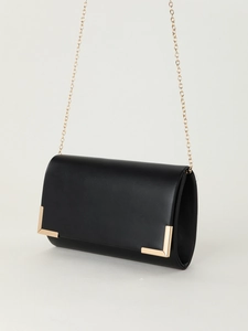 Detail of a black PU leather clutch with gold metal corners and a fine gold chain strap