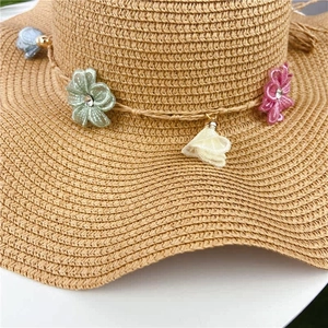Close-up of a woven straw hat featuring colorful fabric flowers and rhinestone details