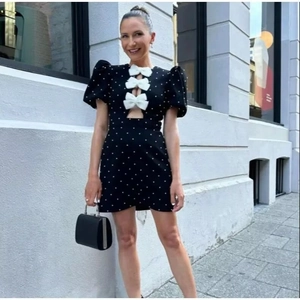 Detail view of black polka dot dress with white bows, puff sleeves and V-neck cutout