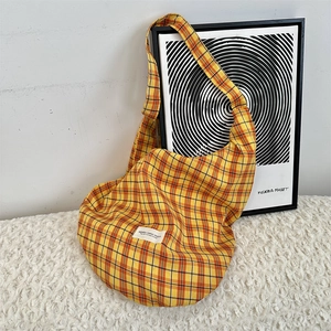 Detail of yellow checkered canvas shoulder bag with branded patch in a modern home setting