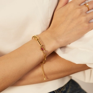 Gros plan détaillé du bracelet trombone doré orné de zircons rouges et roses