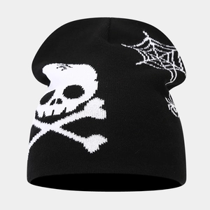 Macro view of knit beanie featuring white skull and crossbones with spider web patterns