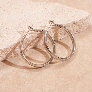 Minimalist silver geometric hoop earrings with polished finish on stone display