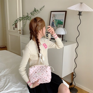 Pochette matelassée rose en tissu tenue par un mannequin dans une chambre lumineuse