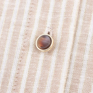 Macro view of striped linen fabric with gold lurex threads and a metallic rimmed button