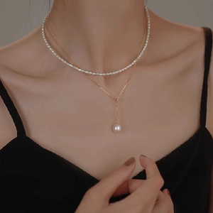 Elegant double-layered gold chain necklace with freshwater pearls shown on model collarbone