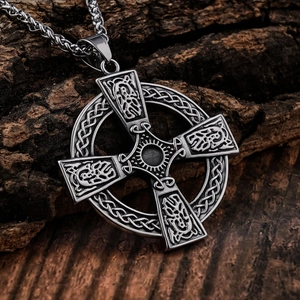 Antique silver Celtic cross pendant with intricate knotwork on dark bark background