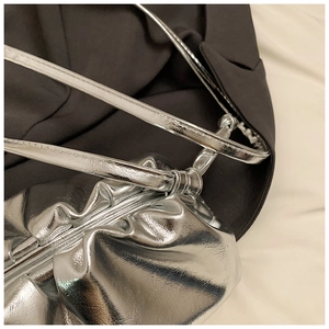 Detailed texture of silver pleated cloud bag with metallic finish and strap connector