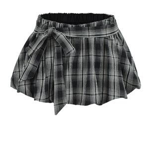 Detail of black and white checkered mini skirt featuring a waist bow and pleated texture