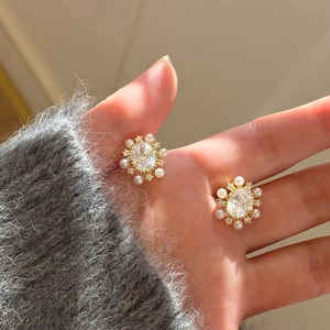 Macro detail of elegant gold plated flower earrings with pearls and zircon stones