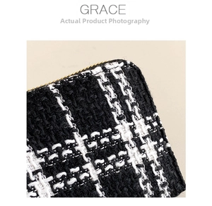 Macro detail of black and white tweed fabric with gold metal zipper on a small wallet