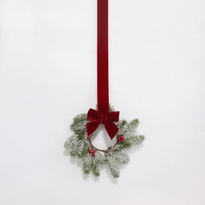 Close-up of Christmas wreath with pine needles, red berries, cones and velvet bow
