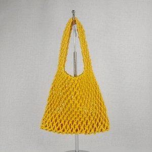 Detail of bright yellow macrame net beach bag with thick hand-woven cotton rope knots