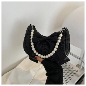 Detail of elegant black lace handbag featuring a large satin bow and pearl bead handle