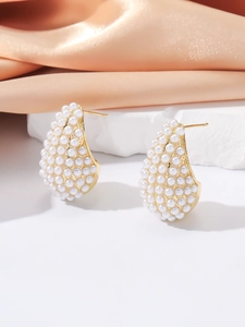 Macro detail of elegant golden teardrop earrings encrusted with small white pearls