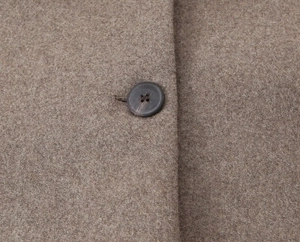 Detail of wool blend fabric texture and dark round button on brown short coat
