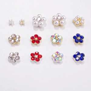 Detail showing colorful 3D five-petal nail charms with rhinestones and pearls set in gold