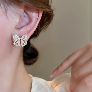 Close-up of bow earrings with pearls and crystals on a model for elegant princess style