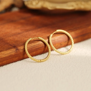 Close-up of textured gold stainless steel hoop earrings with secure latch closure