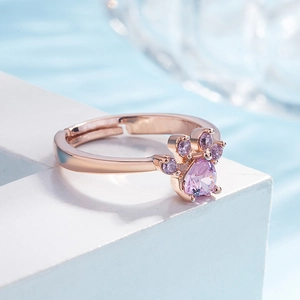 Detailed view of rose gold cat paw ring with lavender cubic zirconia on a white pedestal