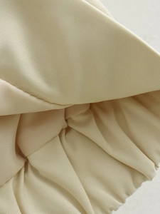Vista dettagliata della trama del tessuto a coste beige e polsino elastico della giacca