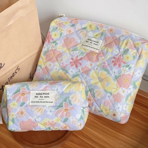 Macro detail of lavender quilted floral makeup bags with soft cotton texture and label