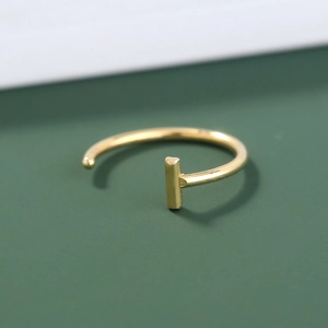 Detailed macro view of golden U-shaped stainless steel nose ring with T-bar design