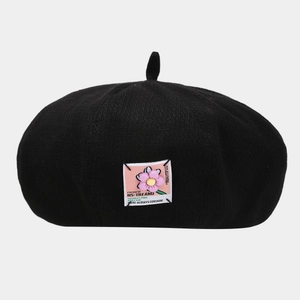 Detail of black beret with pink floral applique and decorative patch text embroidery