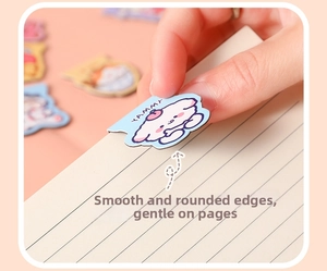 Close-up of cute cartoon dog magnetic bookmark being clipped onto a notebook page