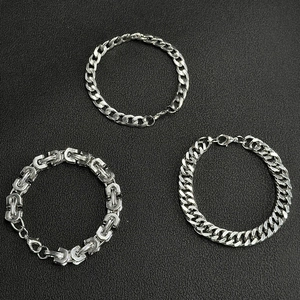 Three-piece silver Cuban and Byzantine chain bracelets set for men on black background