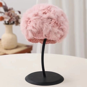 Pink hand-crocheted rabbit fur knit beanie with fluffy pompom on a display stand
