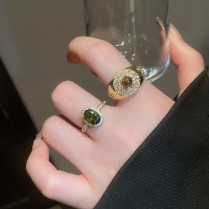 Close-up of 18k gold plated tiger eye ring and green zircon stone on a model hand