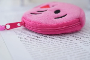Close-up of pink plush coin purse with embroidered cartoon face and zipper detail