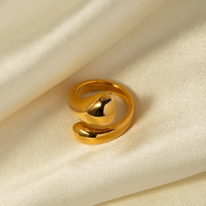 Macro shot of minimalist gold teardrop open ring on soft silk fabric texture