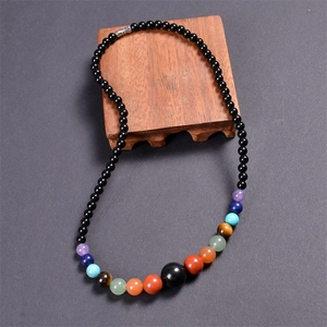 Detail of 6mm multi-color agate beads on wood tray with black chakra stones