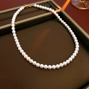 Détail d'un collier de perles blanches avec fermoir doré sur un plateau à bijoux