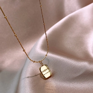 Elegant gold titanium steel bar necklace with beaded chain on soft silk background
