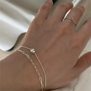 Detail of silver S925 double layer paperclip bracelet and minimalist zircon ring on hand